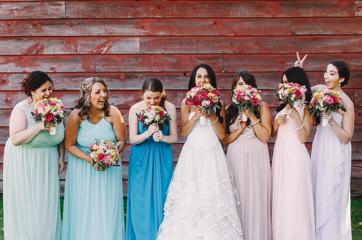 Bride and bridesmaids grimace while hiding their faces behind th