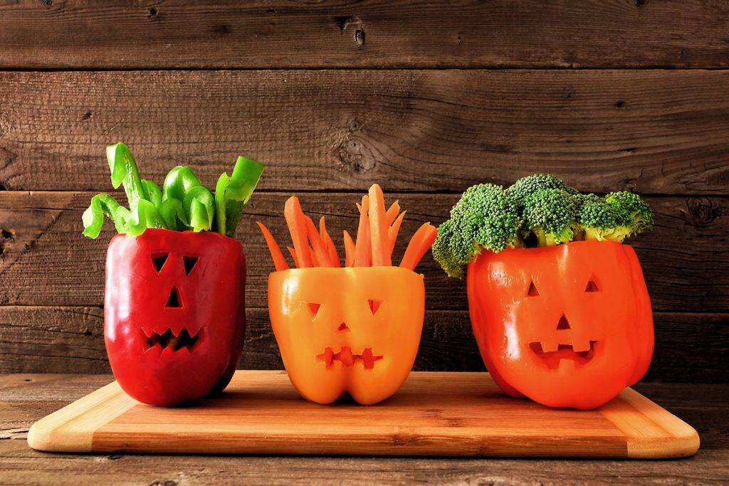 Halloween vegetables and dip in Jack o Lantern peppers on a wood background