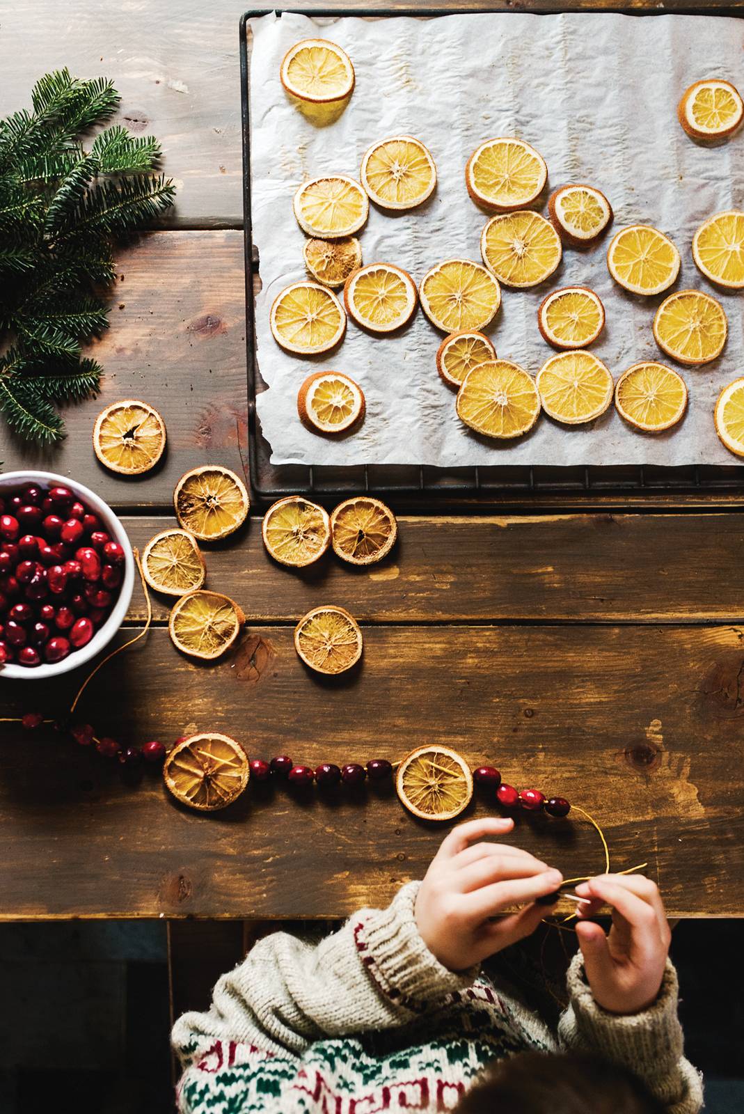 Stock Photo Of A Child Making A Christmas  Garland With Cranberries And Dried Oranges, From Above