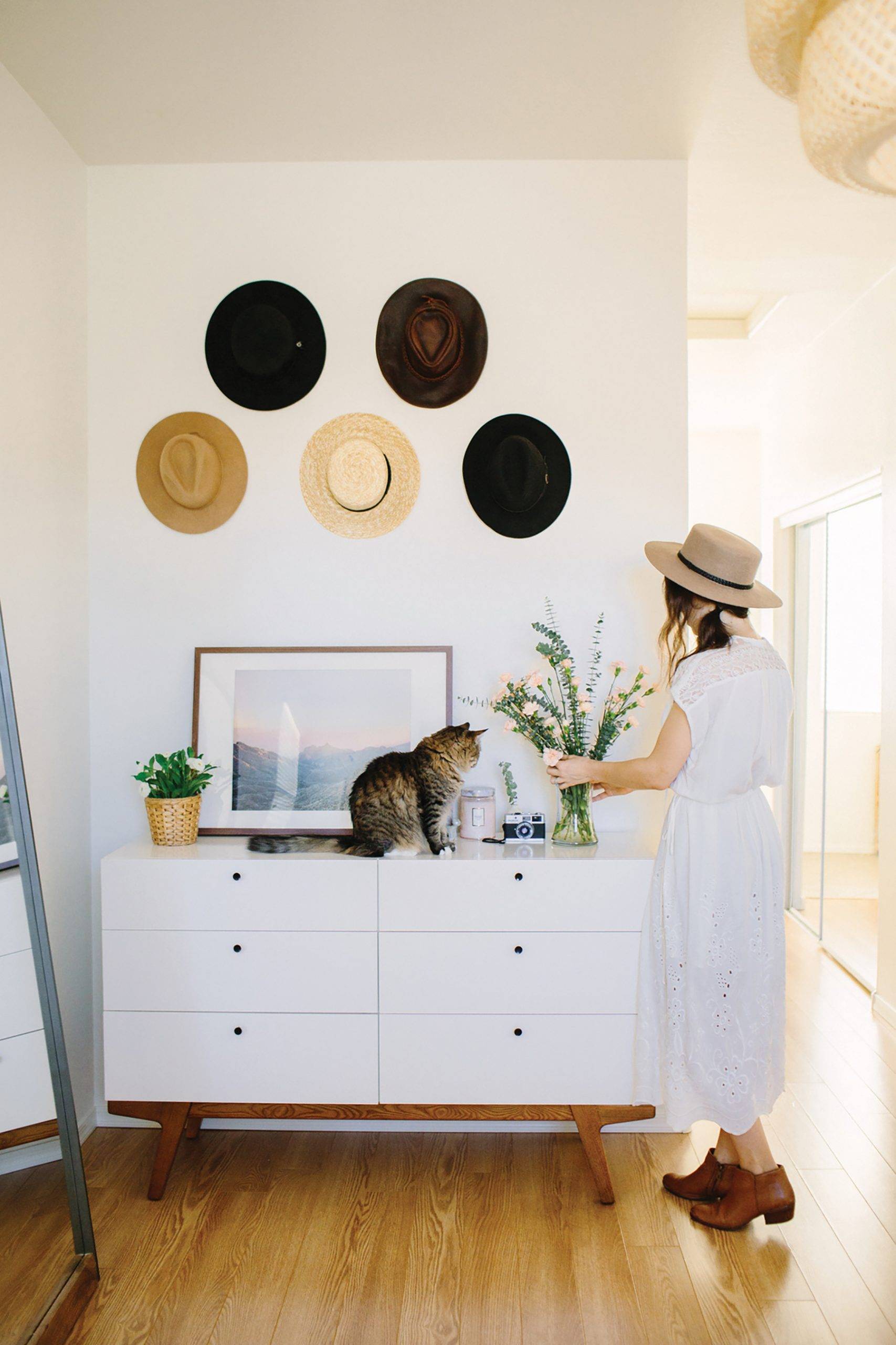 Woman Arranging Flowers On Dresser In Bedroom