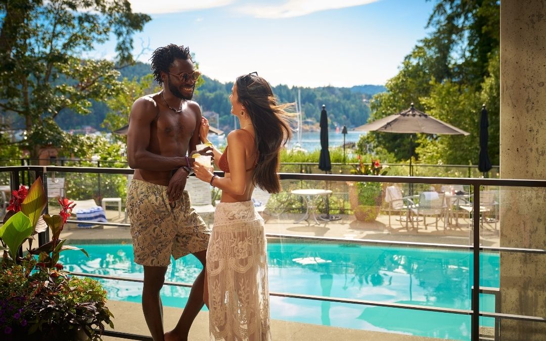 couple beside heated outdoor pool overlooking calm ocean waters